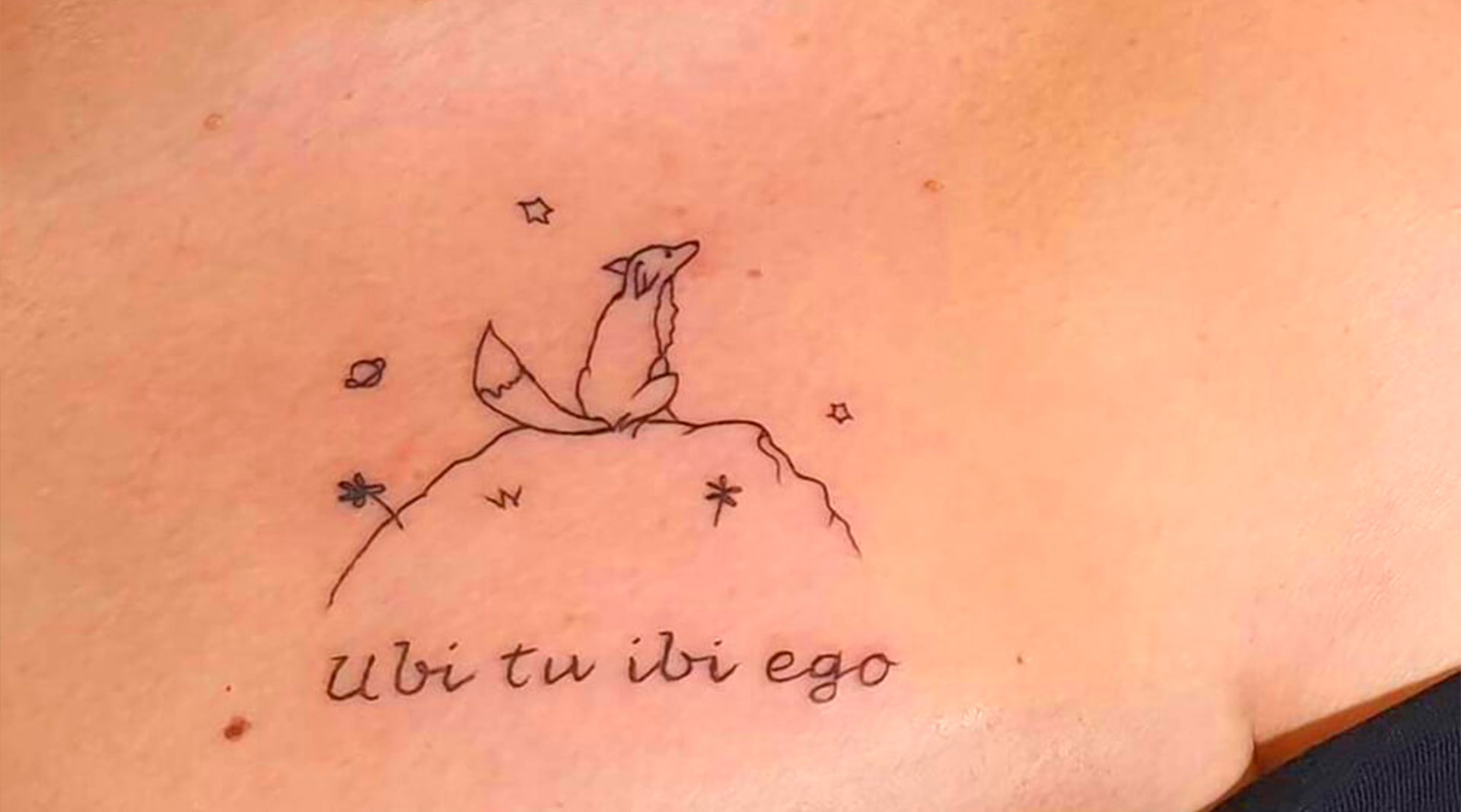 Tatuaggio ubi tu ibi ego con volte di spalle seduta su un sasso e le stelle intorno